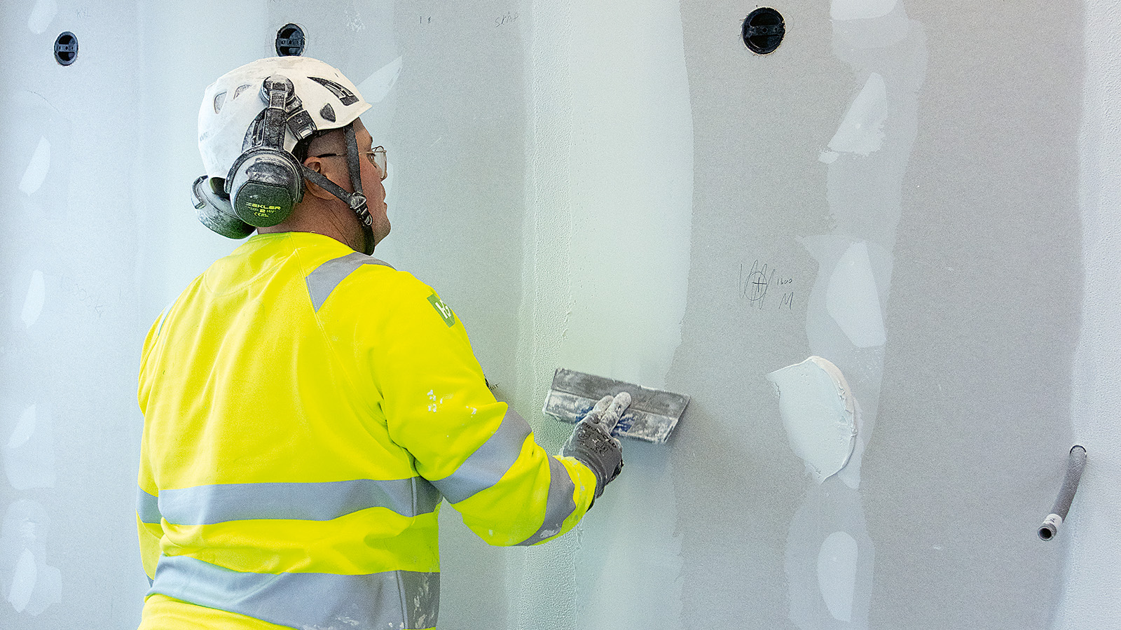 En m&aring;lare spacklar en v&auml;gg